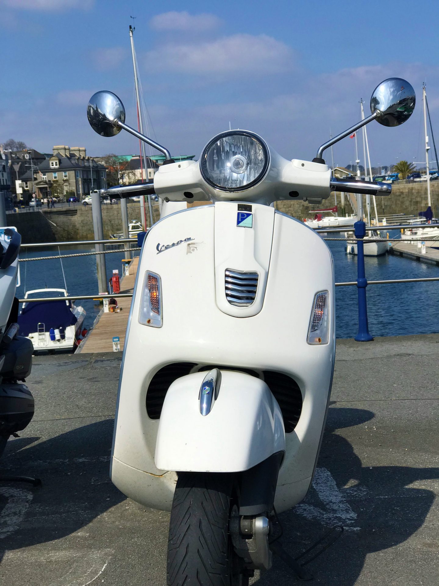 A white Vespa GTS in St Peter Port harbour