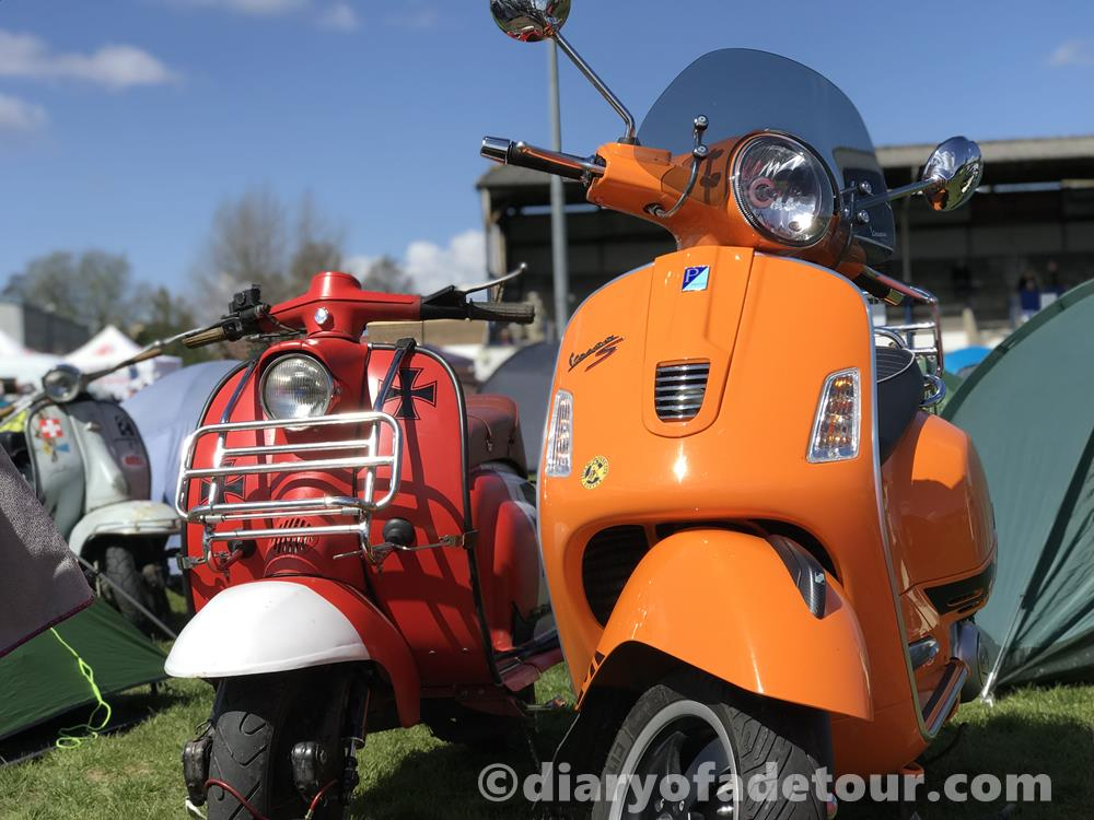 Red Series 1 Lambretta parked next to an orange GTS Vespa