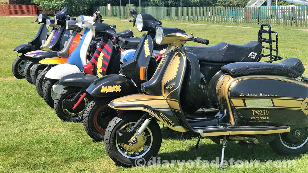 A row of scooters with a blue and gold Lambretta at the front