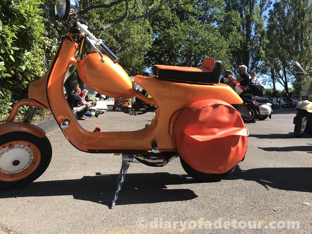 Bright orange Vespa chopper with spare wheel, and Wotsit theme.