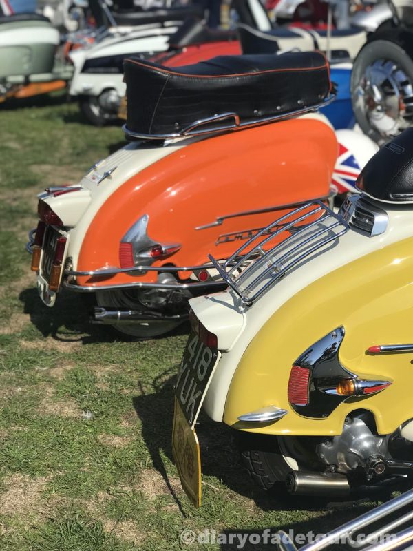Two vintage Lambrettas, one with orange side panels and one with yellow side panels