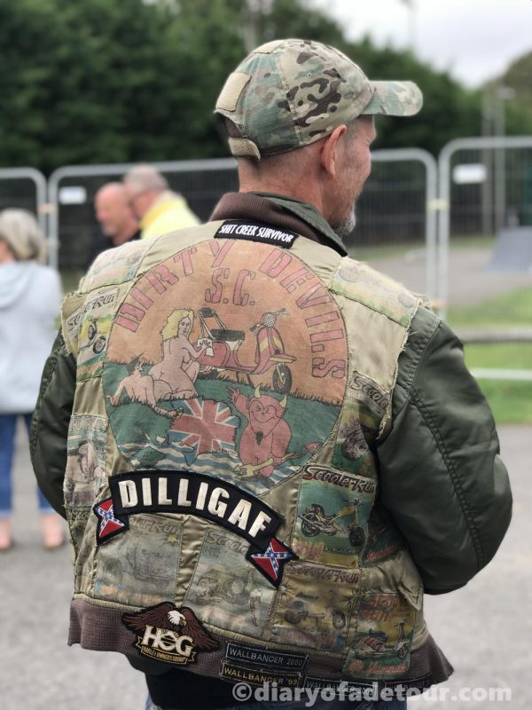 Scooterist wearing a flight jacket covered in scooter patches including a club patch from Dirty Devils scooter club