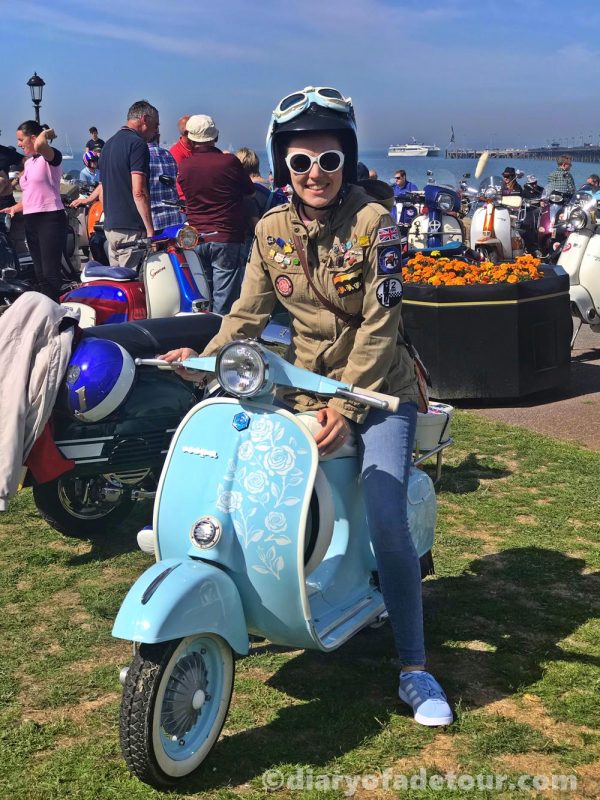 Scooterist on a sky blue smallframe Vespa on the green at Ryde