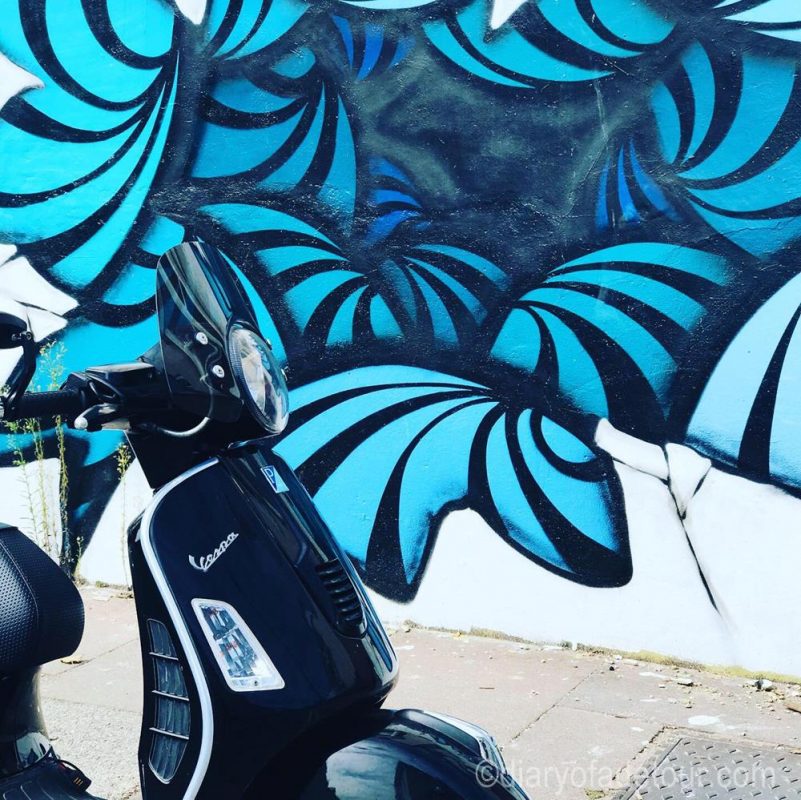 Black scooter with an art hole mural in Brighton.