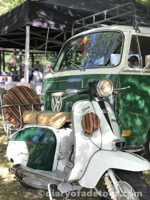 Vintage Lambretta SX parked in front of a green classic VW camper van
