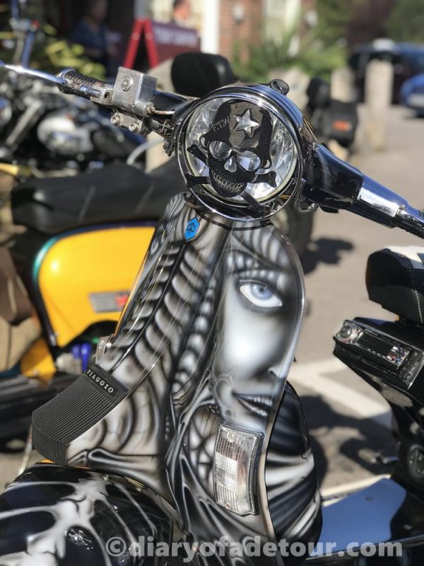 A custom Vespa, The Relic, with murals of a face and bones on the legshields and front mudguard.