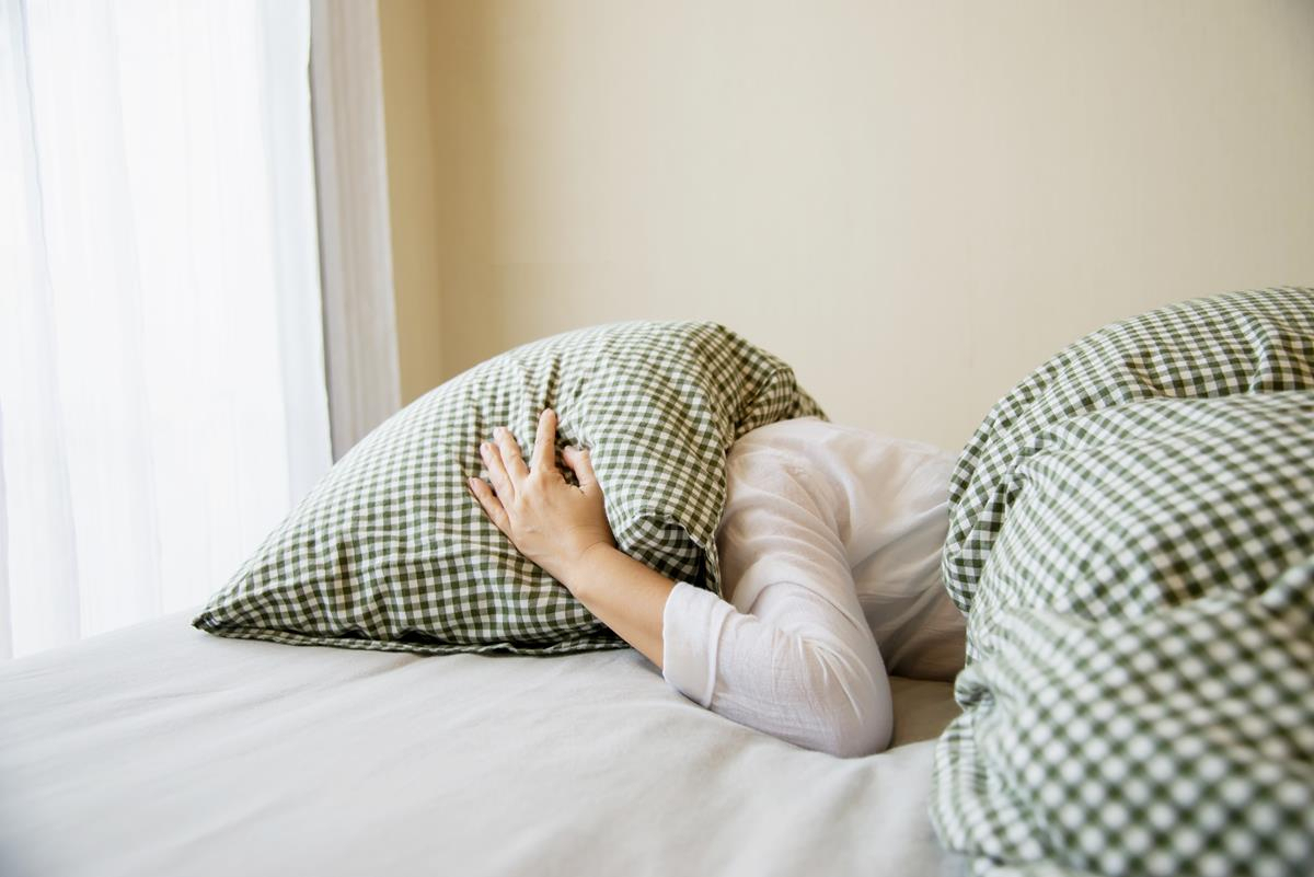 Lady with pillow on her head representing menopausal insomnia
