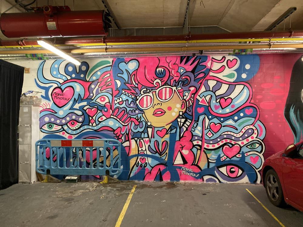 Psychodelic pink, white and blue mural by Manic Minotaur in a car park