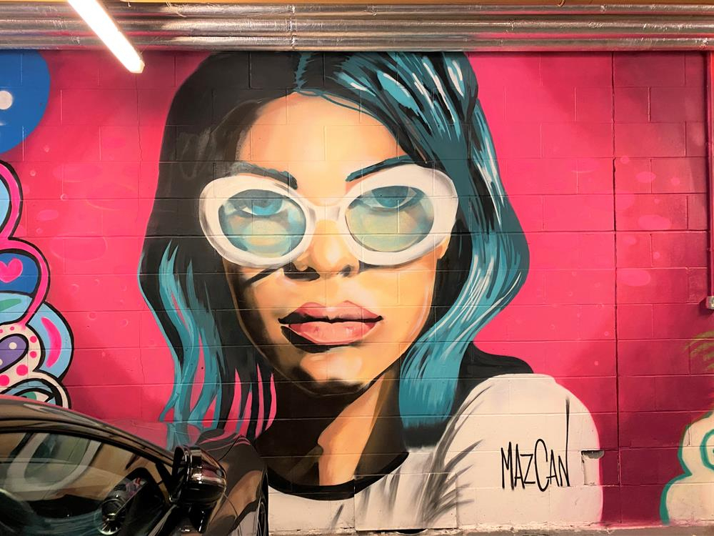 Mural of a woman's face by Mazcan underneath the My Brighton Hotel