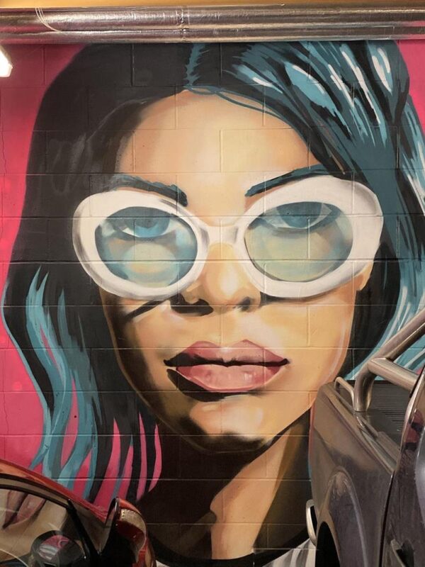 Mural of a woman's face by Mazcan underneath the My Brighton Hotel