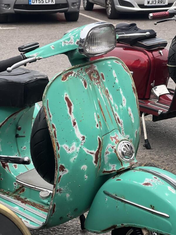 A distressed vintage Green vespa scooter