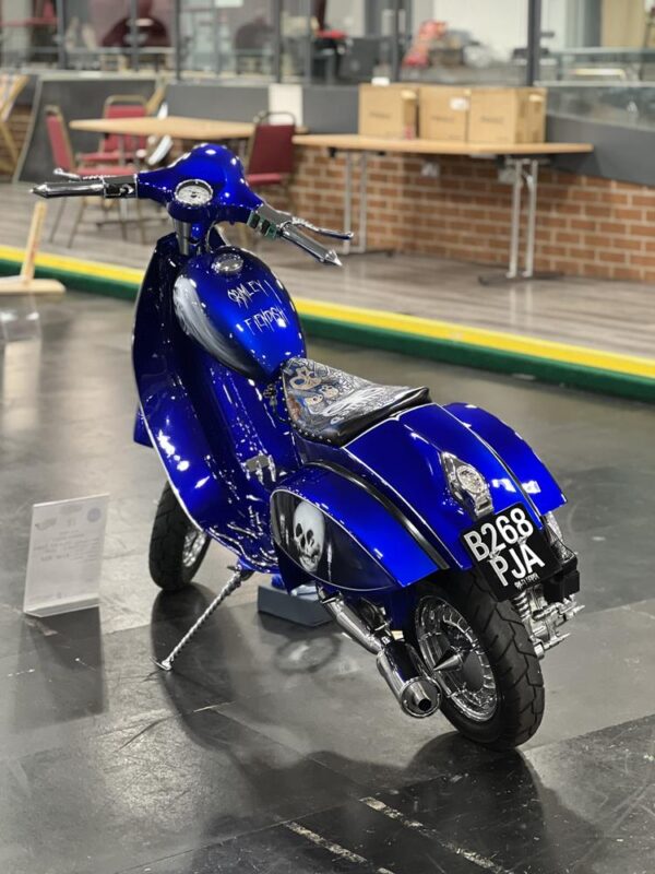 A blue cutdown Vespa with extended forks and murals of skulls, with a theme of the band The Damned.