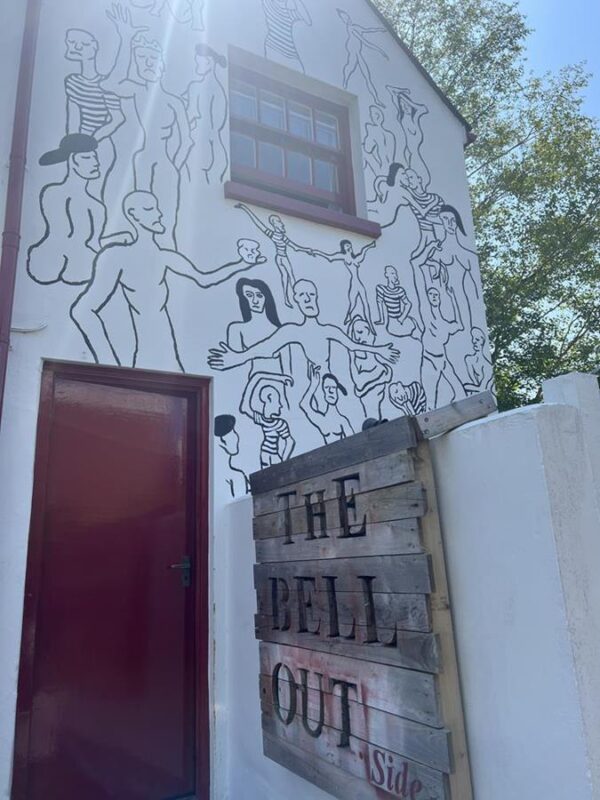 A mural on the side of The Bell pub in Chichester, depicting the outlines of mainly naked figures.