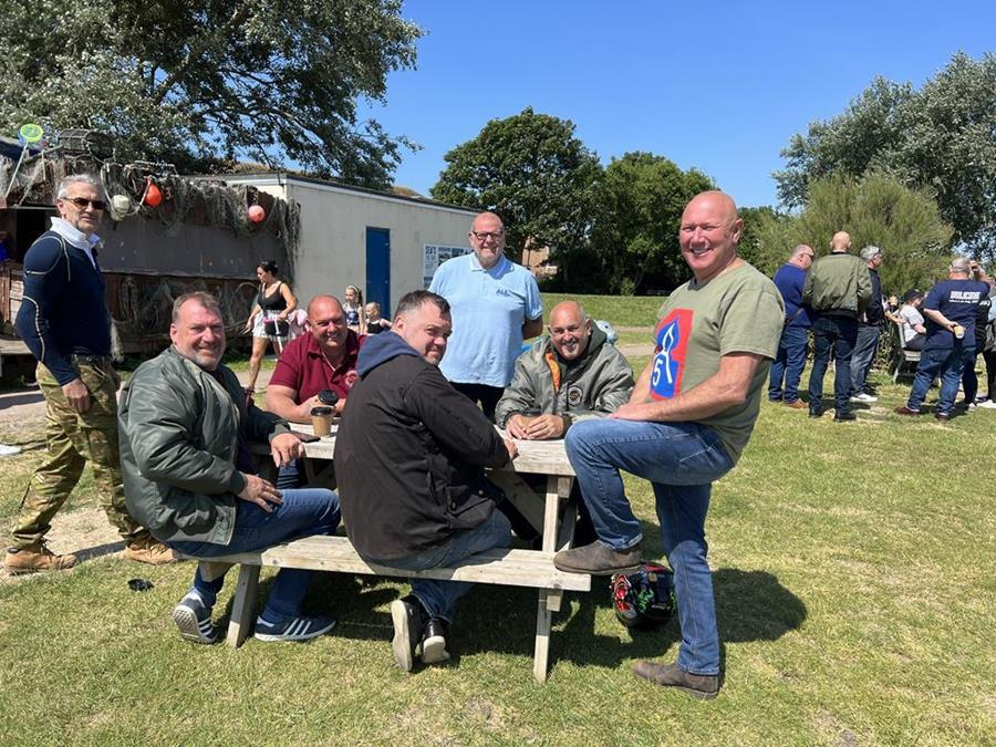 A few of the A5 scooter club sitting at a picnic bench at East Beach car park, at the Selsey scooter meet.