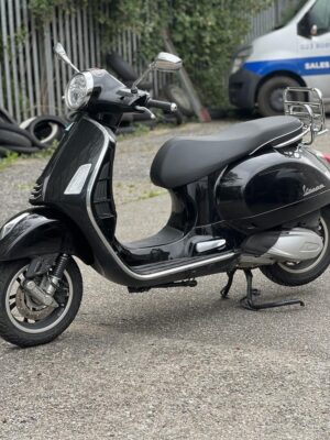 Side view of a black Vespa GTS300 HPE2 parked at the rear of Dearden Motorcycles in Hythe
