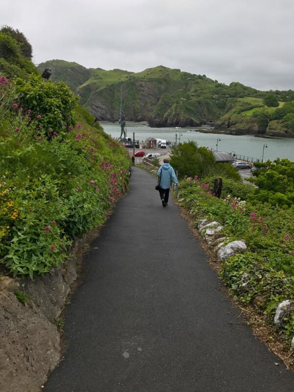 A path leading to Ilfracombe harbour with scenic hills in the background.