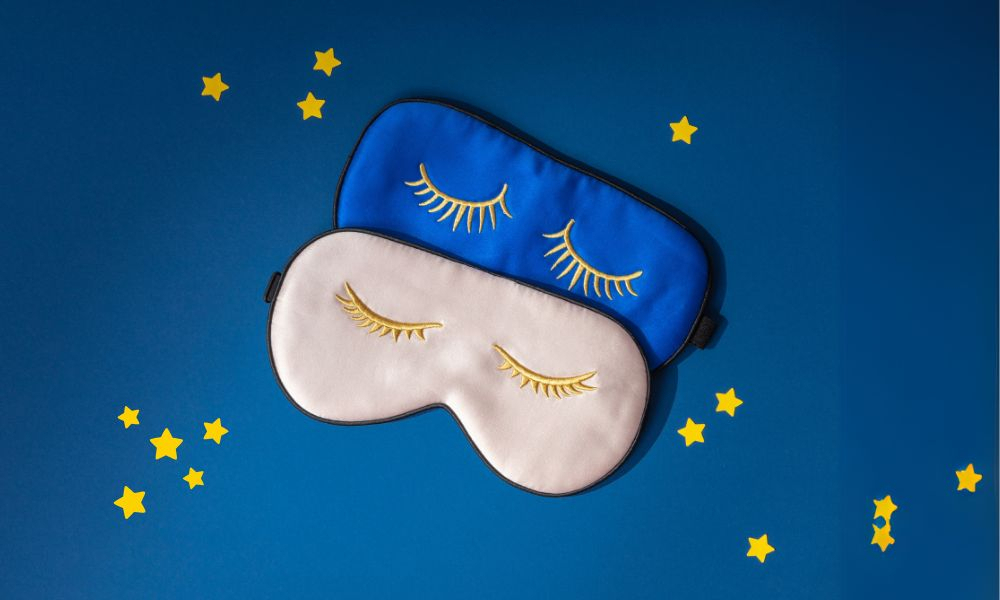 Two blue and white sleep masks on a blue background with yellow stars.
