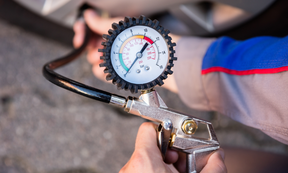 Close-up of a hand using a tyre pressure gauge to check the tyre pressure in a car tyre