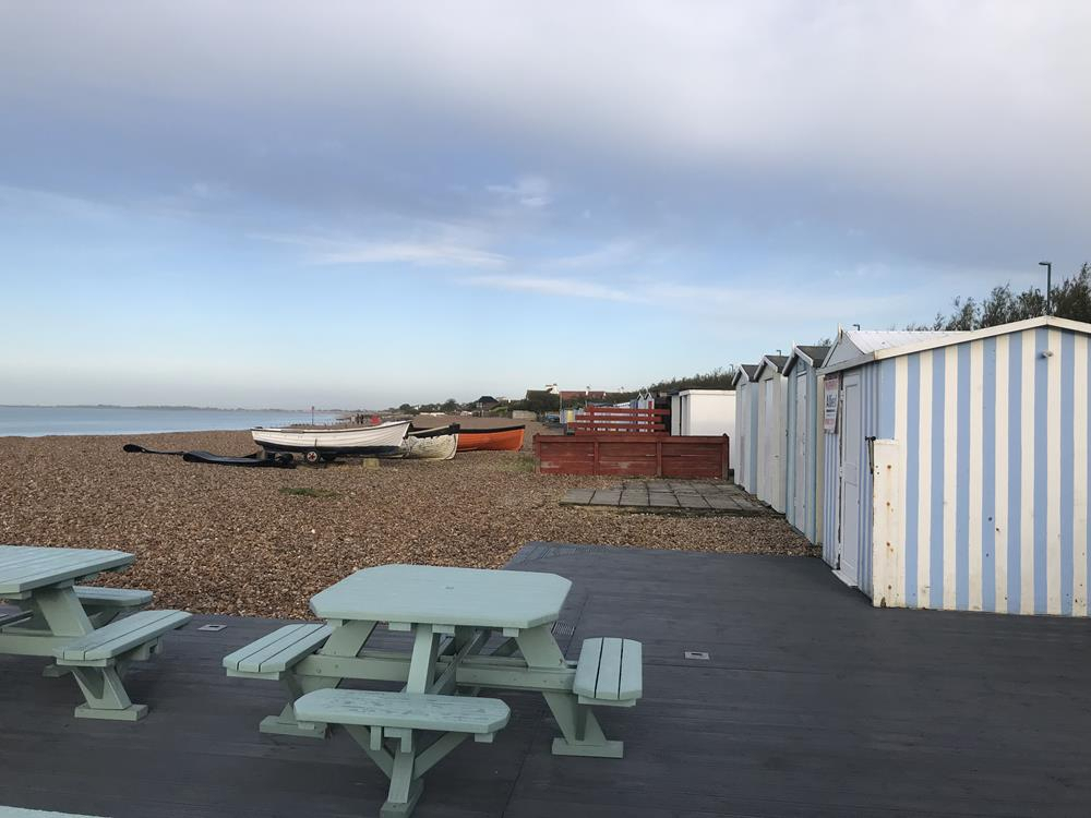 Picnic benches on the beach with beach huts in the background